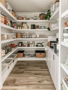 an organized pantry with white shelving and wooden floors