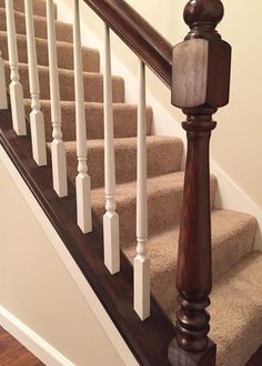 a wooden banister sitting on top of a set of stairs next to a carpeted floor