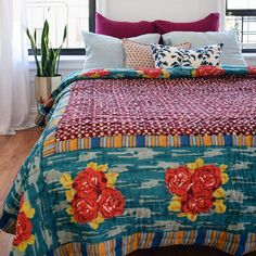 a bed with colorful bedspread and pillows in a room next to a window