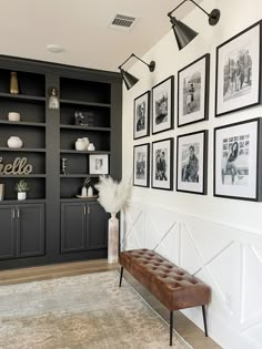 a living room with pictures on the wall and a bench in front of some bookshelves