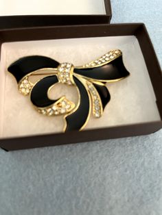 Add a touch of retro to your outfit with this beautiful bow brooch pin. The black enamel and crystal rhinestones give it a vintage vibe, while the yellow gold plating adds a touch of luxury. The brooch is 2.5" in length and features a pavé setting style with round rhinestones. Perfect for any occasion, this brooch is a great addition to your jewelry collection. Whether you're dressing up or down, it's sure to make a statement. So why wait? Add this stunning vintage brooch to your cart today! Bow Brooch, Pave Setting, Vintage Vibe, Vintage Brooch, Vintage Vibes, Black Enamel, Vintage Brooches, Vintage Watches, Gold Plating