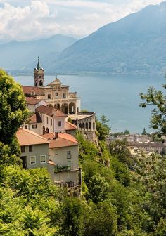 an old building on the side of a hill with trees and mountains in the background