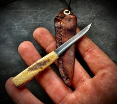 a person holding a knife in their hand with a piece of wood attached to it