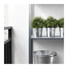 three metal buckets with plants in them sitting on a shelf next to a trash can