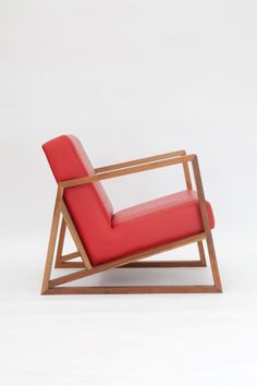 a red chair sitting on top of a white floor next to a wooden framed object