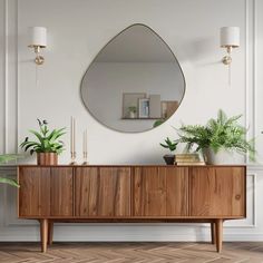 a wooden cabinet with plants on top and a round mirror above it in a white room