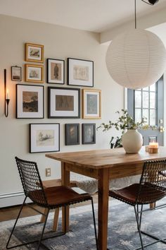 a dining room table with chairs and pictures on the wall