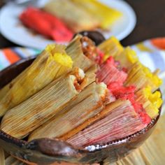 corn on the cob with red sauce in a wooden bowl next to other plates