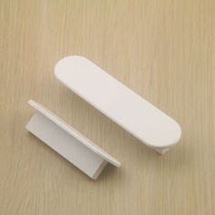 two white plastic objects sitting on top of a wooden table