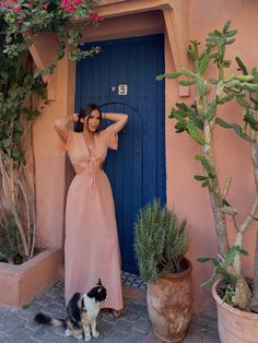 a woman standing in front of a blue door next to a black and white cat