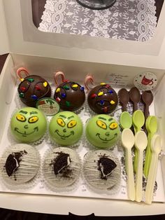 there are many cupcakes in the box with faces and spoons on them