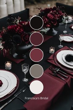 the table is set with red and white plates, silverware, and flowers in vases