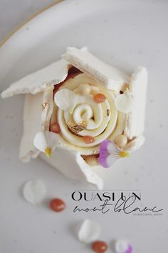 a white plate topped with a small cake covered in frosted icing and flowers