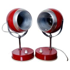 two red and white lamps sitting next to each other on top of metal bases,