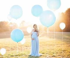 a woman in a blue dress is holding balloons and posing for a photo on her phone