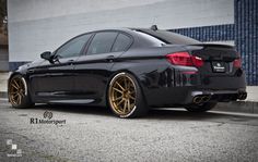 a black car with gold rims parked in front of a building