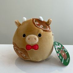 a brown stuffed animal with a red bow tie on it's head sitting next to a tag