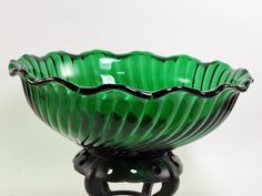 a green glass bowl sitting on top of a black stand