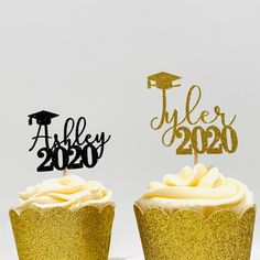 two cupcakes with gold frosting and graduation decorations