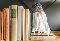 a book shelf with books and a tasseled hat sitting on top of it