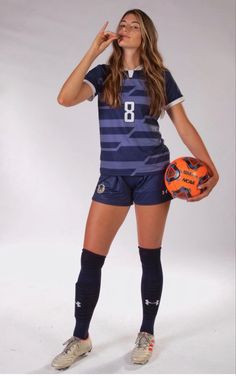 a female soccer player posing for a photo with an orange ball and glove in her hand