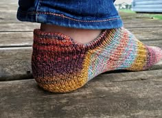 a person wearing colorful socks and blue jeans stands on a wooden deck with their feet in the air