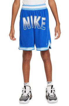 a young boy in blue shorts and white shirt with the word nike written on it