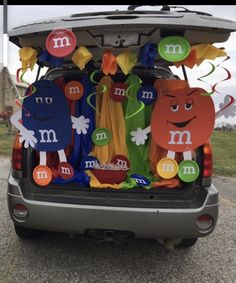 the trunk of a car decorated with paper cutouts and decorations for an m & m party