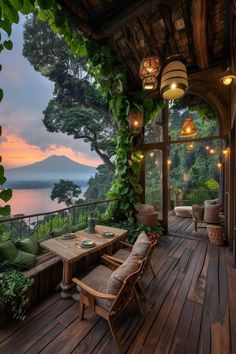 an outdoor deck with chairs and tables overlooking the water at sunset or dawn, surrounded by greenery