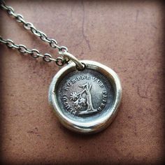 a wax seal necklace with an image of a woman on it's back side