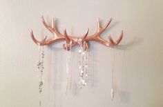 a deer's antler with crystal beads hanging from the side on a wall