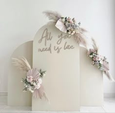 an all you need is love sign with flowers and feathers attached to the back of it