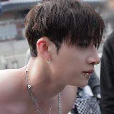 a young man with short hair and piercings on his ear looking off to the side