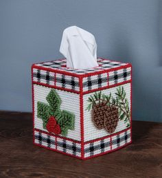 the tissue box is decorated with holly and pine cones on it's plaid cover