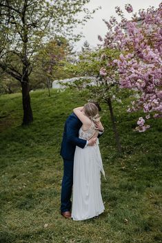 a bride and groom embracing in front of blooming trees