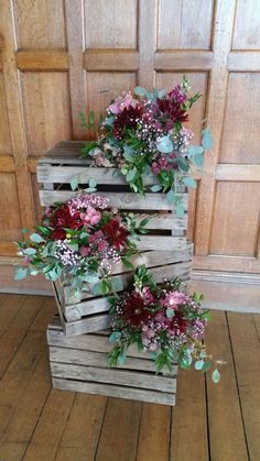 three wooden crates with flowers in them sitting on the floor next to a wood door