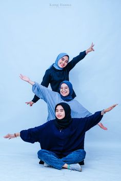 three women in hijabs are sitting on the ground and posing for a photo