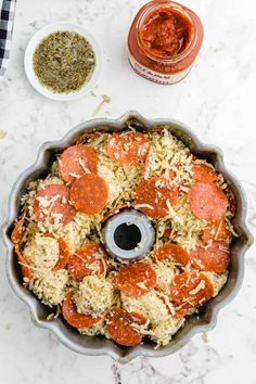 pepperoni and cheese pizza in a pan on a table with seasoning next to it