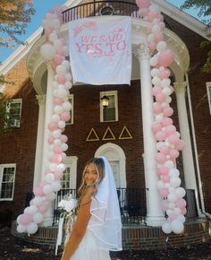 a woman standing in front of a building with balloons and a sign that says we said yes to