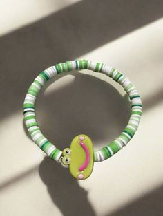 Description Get ready to add some playful charm to your accessories with this Green Smiling Frog bracelet! This shades of Green and White and stretchy beaded bracelet features a center bead in the shape of a happy cartoon frog with surrounding Clay Beads beads. Perfect to add a touch of whimsy to any look! Details fits 7"-7 ½ " wrists green Plastic Smiling Frog: 17.4mm x 24.6mm x 7mm Shades of Green and White Clay Beads Features One of a kind, fashion jewelry, everyday jewelry Great gift for tha Fun Green Stretch Bracelet For Friendship, Playful Green Adjustable Bracelets, Adjustable Green Playful Bracelets, Fun Green Beaded Bracelets, Fun Green Bracelet Jewelry, Green Novelty Bracelets With Round Beads, Fun Green Beaded Bracelets For Friendship, Fun Green Beaded Bracelets With Round Beads, Adjustable Green Fun Jewelry