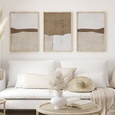 a living room filled with white furniture and paintings on the wall above it's coffee table