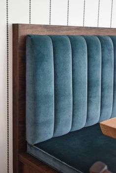 an upholstered headboard on a wooden bed with blue velvet and beading