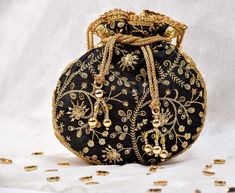 Black Potli Bag with Pearl Handle Strap With its classy zari work and a pearl handle strap all in gold this Black Potli Bag is ideal for this wedding season. Fabric Raw Silk Color Black Embroidery Zari Work in Gold Size amp Dimensions Height - 8 inWidth - 7.5 inDepth - 1.5 in Strap Pearl Handle Strap Closure Tasseled Drawstring Compartments Single compartment Care Wipe with a soft clean amp dry cloth to remove dust When not in use store it in a dust bag for longer product life Avoid liquid expos Bridal Mask, Potli Bag, Raw Silk Fabric, Ethnic Bag, San Ramon, Potli Bags, Black Embroidery, Zari Work, Vintage Purses