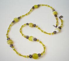 This playful necklace with yellow glass and seed beads and metal spacers in shape of tine flowers can also be worn as a bracelet. The lobster claw clasp is silver-plated.  Length approx.: 24 inches(61 cm) Yellow Spacer Beads For Gifts, Yellow Polished Beads For Gifts, Yellow Beaded Necklace With Spacer Beads, Handmade Yellow Czech Glass Beaded Necklaces, Handmade Yellow Beaded Necklace With Czech Glass, Yellow Czech Glass Beaded Necklace For Gift, Adjustable Yellow Polished Beaded Necklaces, Yellow Czech Glass Beaded Necklaces For Jewelry Making, Yellow Czech Glass Jewelry With Colorful Beads