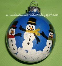 a blue ornament with snowmen painted on the front and sides, sitting on a green surface