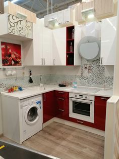 a kitchen with red and white cabinets, washer and dryer in the corner