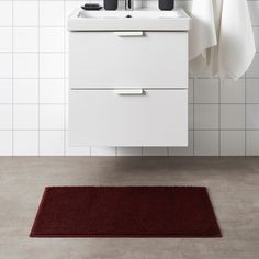 a bathroom with a red rug on the floor and a white sink in front of it