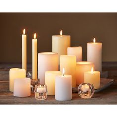 a group of lit candles sitting next to each other on top of a wooden table