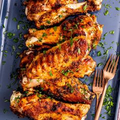 grilled chicken with herbs on a blue platter next to a fork and knife