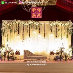 a chair sitting on top of a stage under a chandelier filled with flowers